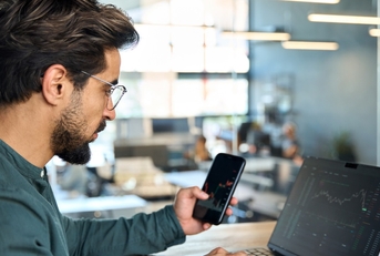 male broker using smartphone and laptop