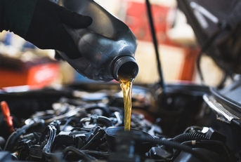 mechanic pouring oil into car engine