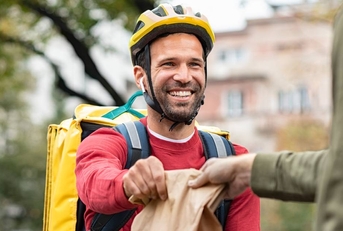 A delivery man handing off a food order.