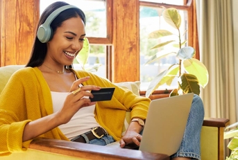 A happy woman sitting on an armchair while using her laptop.