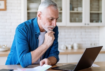 senior man reviewing taxes using laptop