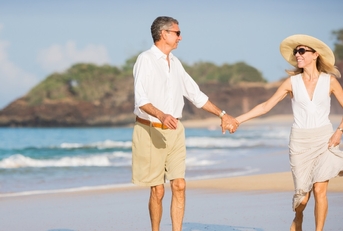 happy senior couple walking on beach