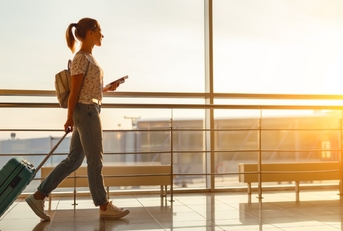 woman at airport window with suitcase 