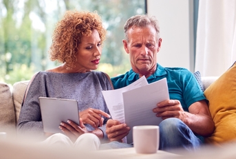 senior couple reviewing bills on couch
