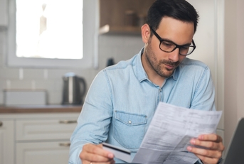 business man reviewing bills holding card
