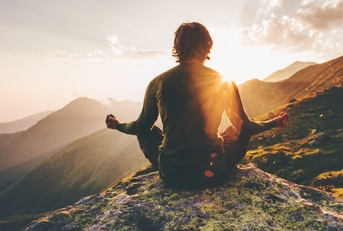male hiker doing yoga at sunset