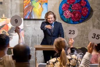 mature male auctioneer pointing at people