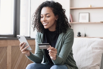 Woman holding her phone in one hand and credit card in the other
