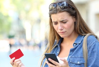 Woman with worried expression holding a credit card