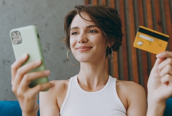 Woman holding a phone in one hand and a credit card in the other