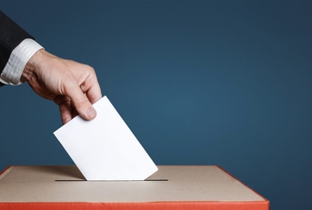 A voter puts a ballot into a ballot box. 