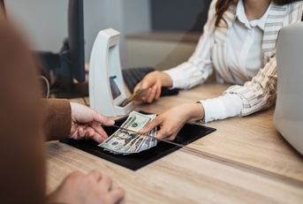 A man receiving money from a bank teller