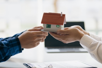 hands holding house sculpture inheritance concept