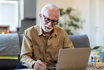 senior man reviewing insurance papers online