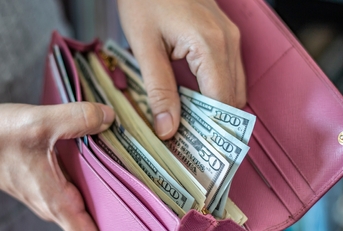 Woman taking out dollar from wallet
