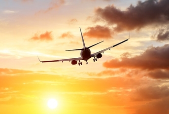 Commercial airplane flying above dramatic clouds during sunset