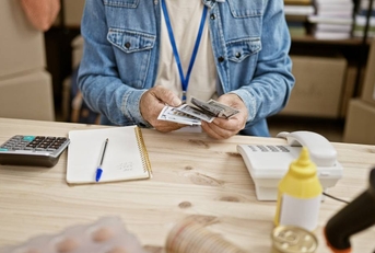 cluttered desk with bills, woman at desk crunching numbers