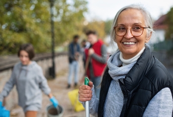 cheerful senior female volunteer cleaning street