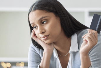Woman holding a credit card looking stressed