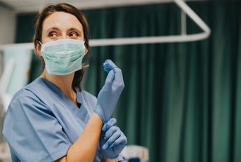 Nurse wearing gloves in hospital room