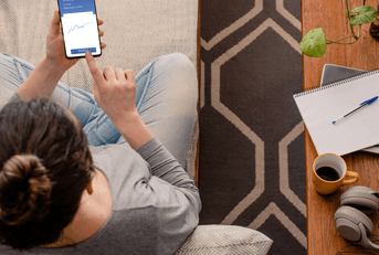 A woman uses a financing app while sitting on her couch.