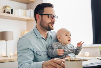 Young father working from home and babysitting his baby boy in the same time.