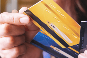 A woman displays three credit cards in her hands.