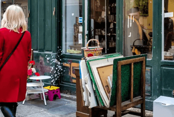 woman walking on sidewalk past antique store