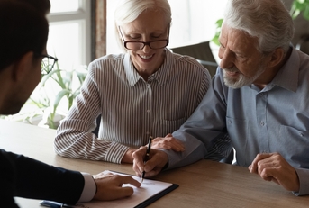pensioners sitting at desk signing