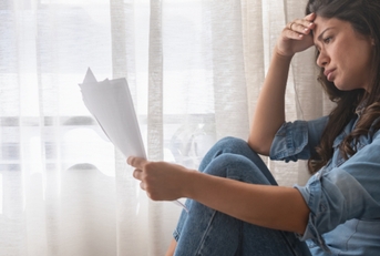 stressed woman holding financial papers