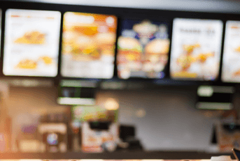 Six blurry overhead menus hang in a fast food restaurant.  