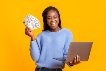 A woman holds a laptop in one hand and fans cash in the other. 