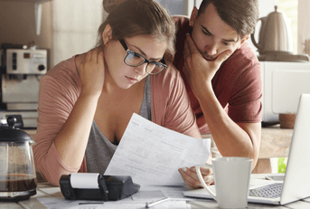 A concerned couple looks over their bills together. 