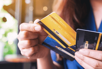 A woman holds three credit cards in her hands. 