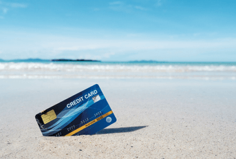 A credit card stuck in the sand on a beach.
