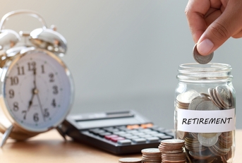 hand putting coins in retirement jar