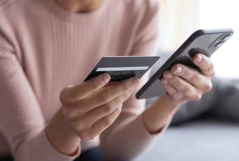 A woman holds her phone and credit card. 