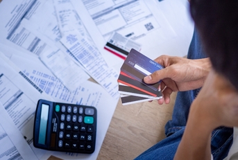stressed man choosing card to pay bills