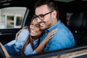 A man and woman hug one another in a car. 