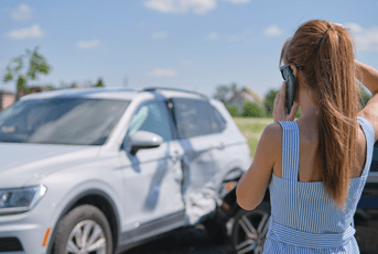 A woman stares at her totaled car.