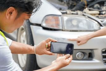A man takes a picture of a car accident.