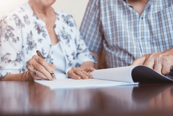 Senior woman signing documents with her husband