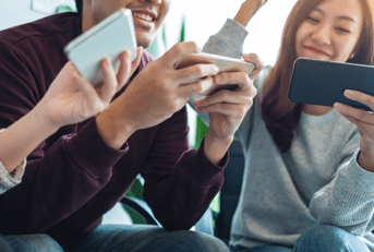 A group of friends cheer while playing games on their phone.