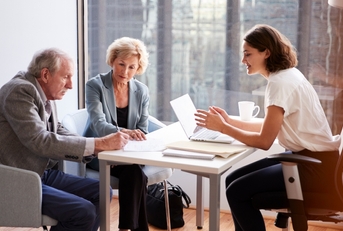 senior couple signing documents with finance advisor