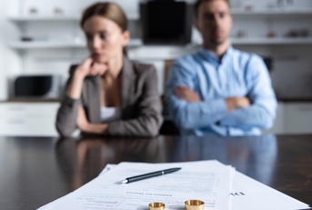 unhappy couple at table with divorce documents