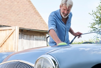 Mature Man Polishing Restored Classic Car Outdoors
