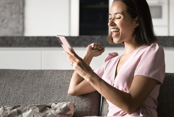 A woman smiles while using her phone.