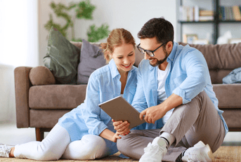 A couple look over plans together while sitting on the floor.