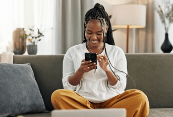 A woman uses her phone while sitting on the couch.