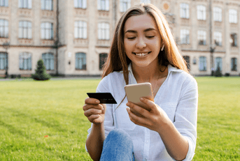 A woman holds her credit card and iPhone. 